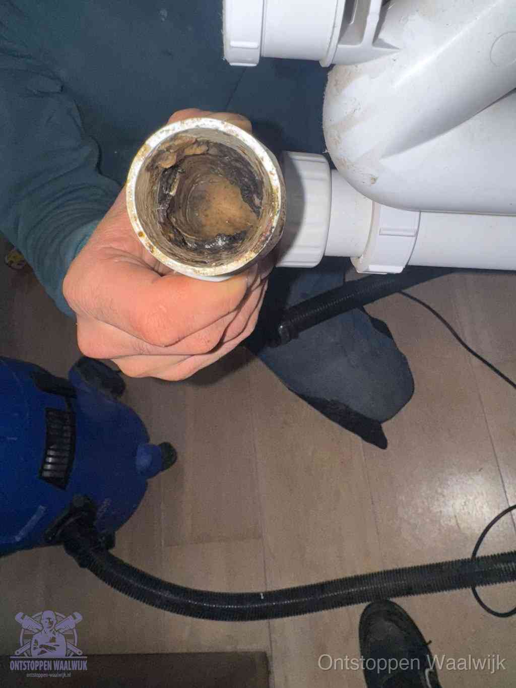 Een losgekoppelde afvoerbuis die van binnen volledig is dichtgeslibd met vet en aanslag, de meest voorkomende oorzaak van een verstopte gootsteen in Waalwijk
