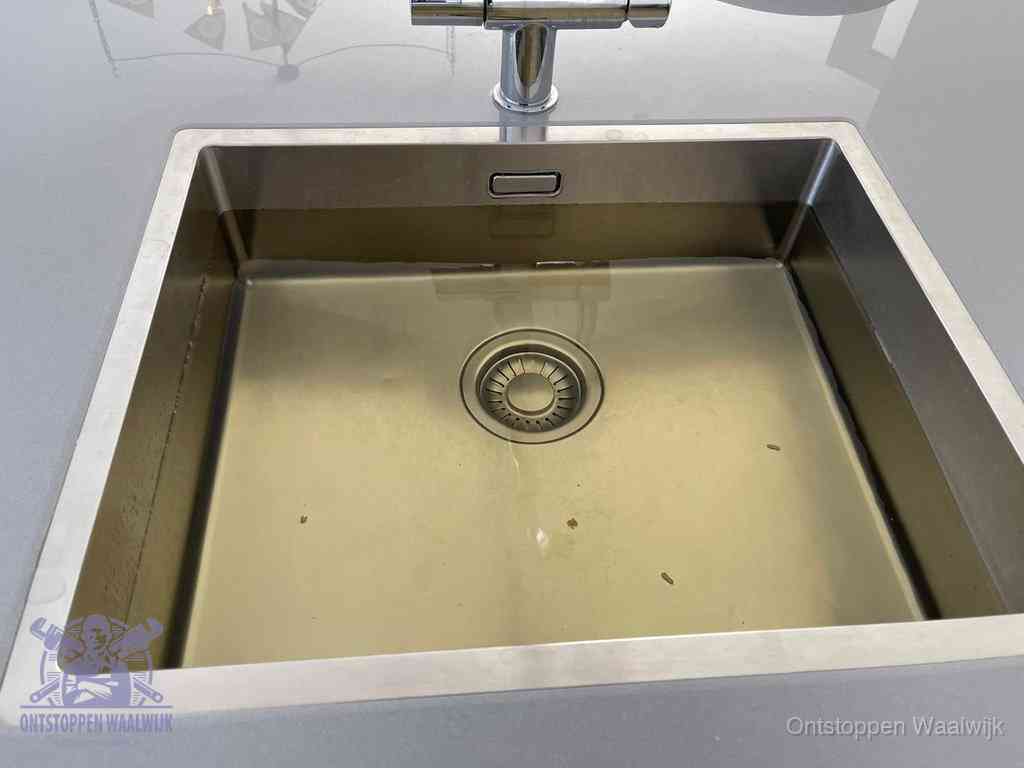 Stilstaand water in een rvs spoelbak dat niet wegloopt, een duidelijk signaal van een gootsteenverstopping in Waalwijk