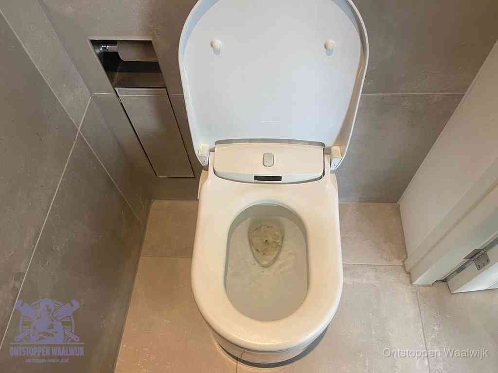 Een wit hangtoilet waarin een prop wc-papier op het water blijft drijven, een duidelijk signaal van een verstopte wc in Waalwijk