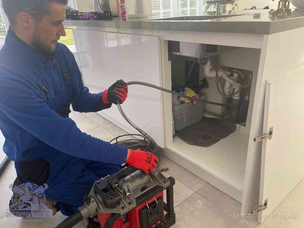 Een monteur reinigt de keukenafvoer grondig met een veermachine om terugkerende gootsteenverstoppingen te voorkomen in Waalwijk