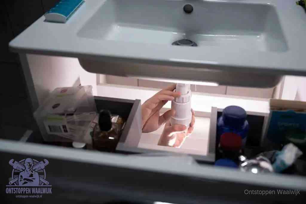 Een pompfles met zeep boven een wastafel in de toiletruimte, de warm water en afwasmiddel-methode om de wc te ontstoppen in Waalwijk