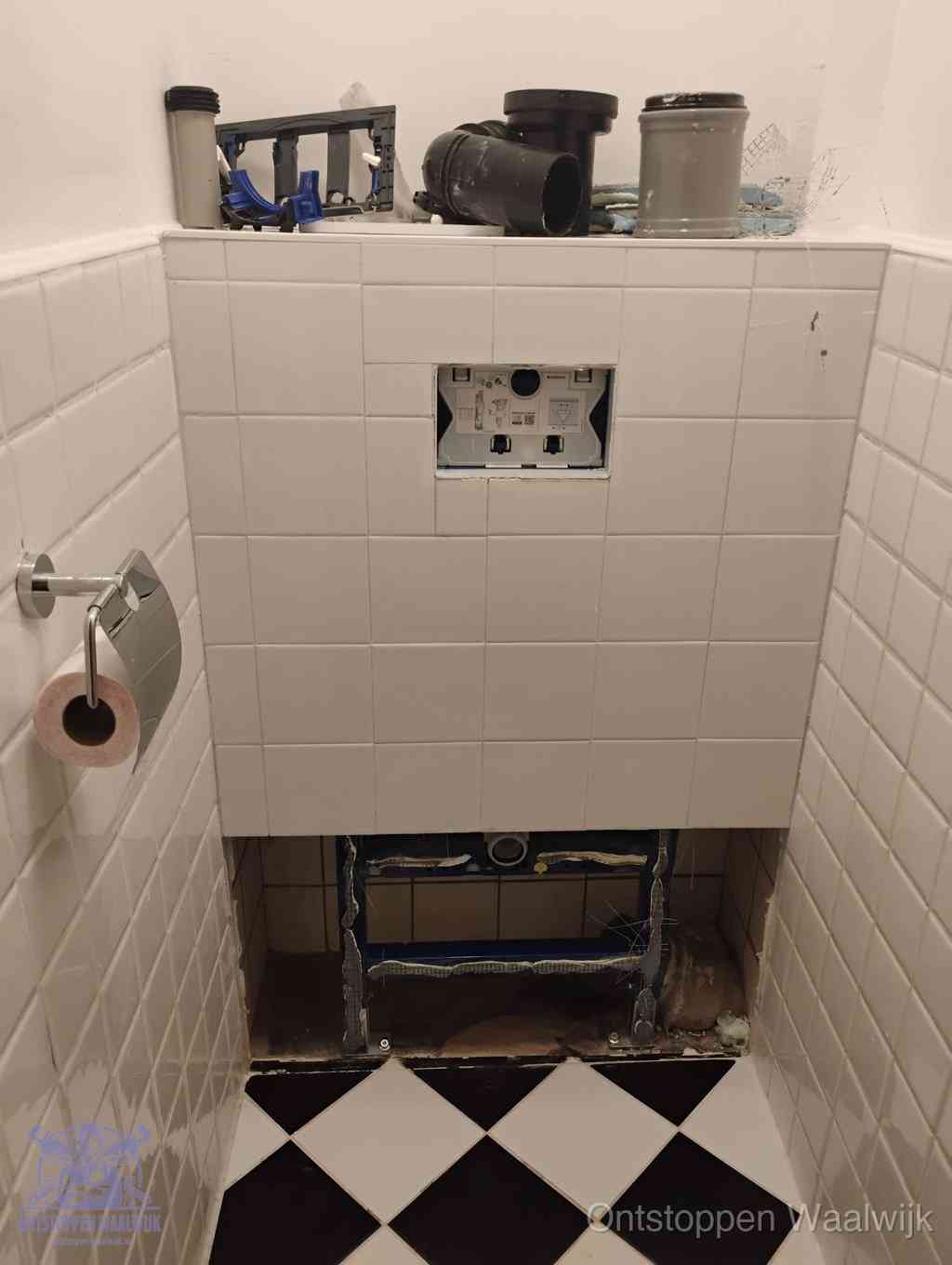 Een toiletruimte waar het hangtoilet en de inbouwreservoir-onderdelen zijn vrijgelegd voor onderhoud, periodiek nazicht voorkomt een wc-verstopping in Waalwijk