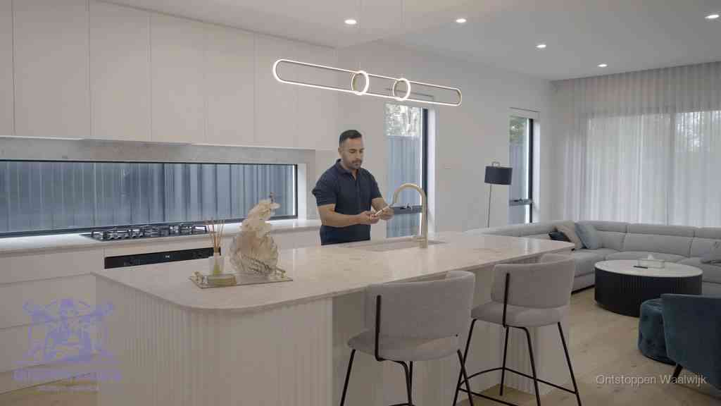 Een bewoner bij de keukenspoelbak die zelf aan de slag gaat met een verstopte gootsteen in Waalwijk